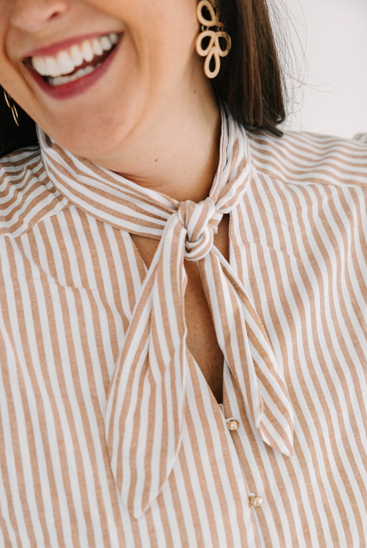white and tan short puff sleeve blouse with tie neck and functional gold buttons