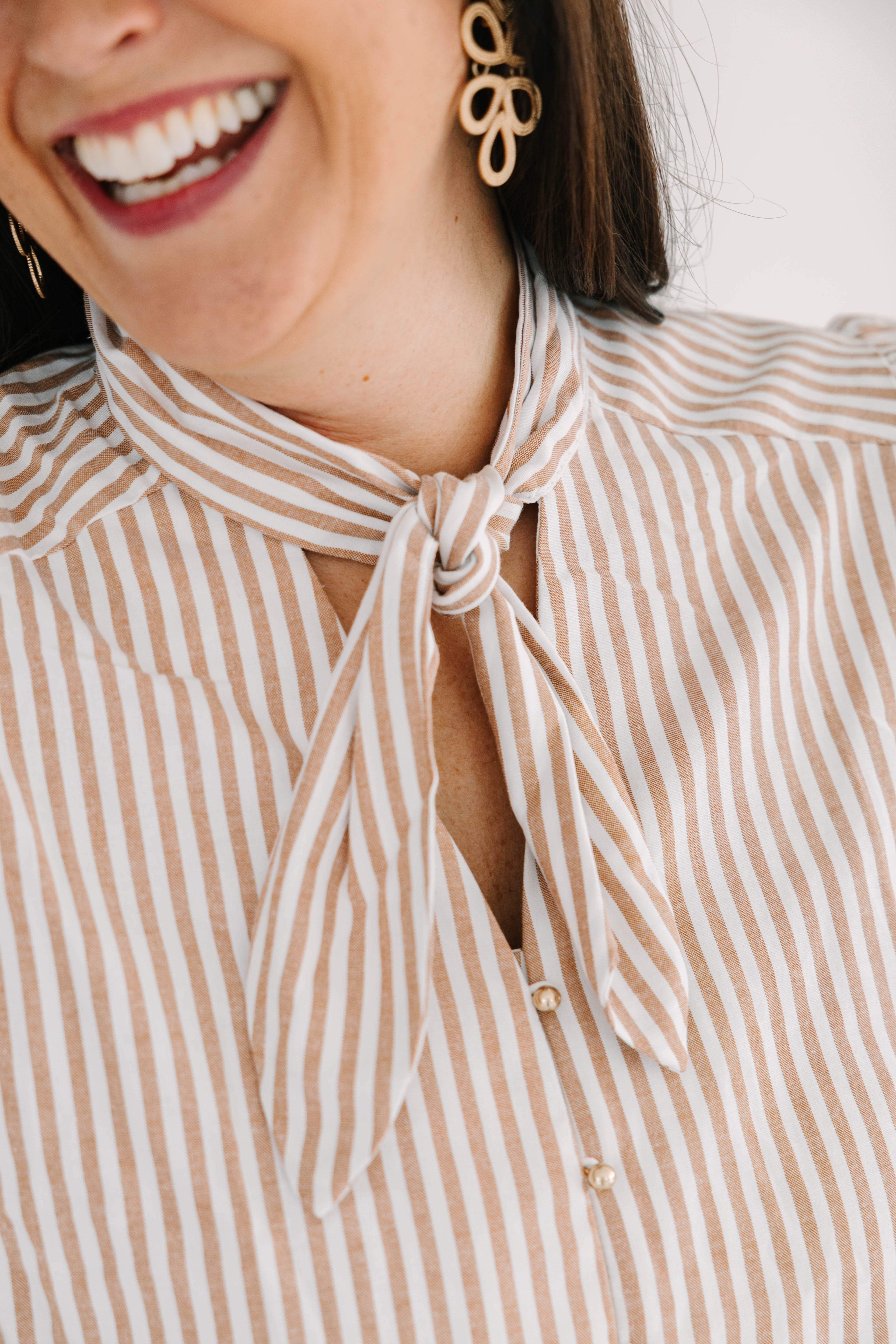 white and tan short puff sleeve blouse with tie neck and functional gold buttons
